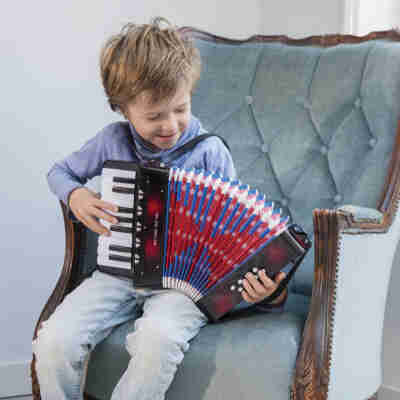 Enfant jouant avec l’Accordéon noir New Classic Toys porté avec ses bretelles
