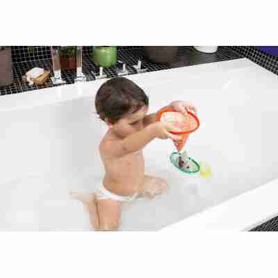 Enfant jouant dans le bain avec les bateaux flottants Lilliputiens et versant de l’eau