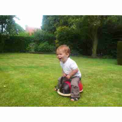 Enfant assis sur un Wheely Bug Coccinelle dans un jardin