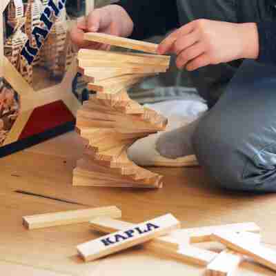 Enfant réalisant une construction en équilibre avec des planchettes Kapla