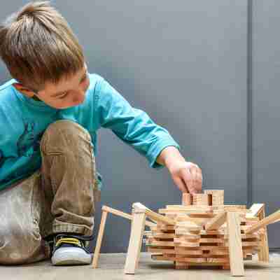 Enfant construisant librement une structure avec des planchettes Kapla