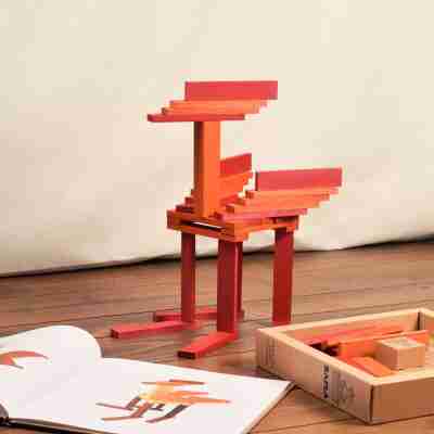 Construction en équilibre réalisée avec des planchettes Kapla orange et rouge