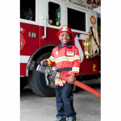 Enfant déguisé en pompier devant un camion de caserne