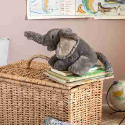 Petit éléphant Moulin Roty posé sur une pile de livres