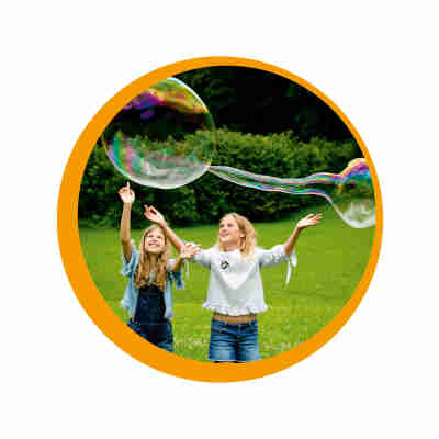 Enfant jouant avec le kit bulles XXL Pustefix en extérieur