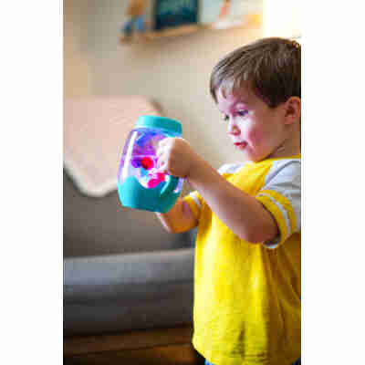 Enfant jouant avec le bocal sensoriel lumineux Glo Pals