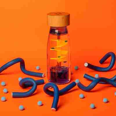 Mise en scène de la bouteille sensorielle Spiral Blue Petit Boum sur fond orange