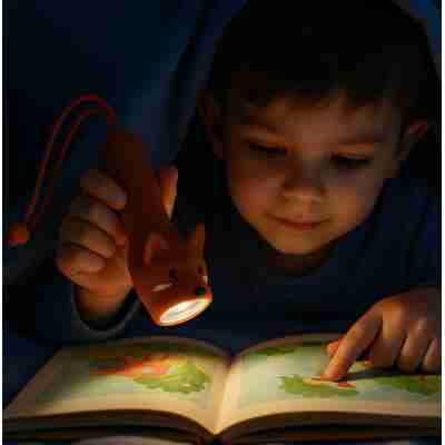 Enfant lisant un livre avec une lampe Little L dans l’obscurité