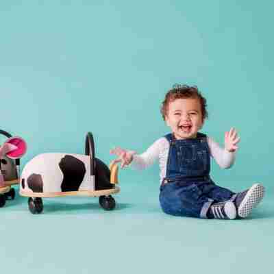Jeune enfant assis à côté d'un porteur Wheely Bug Vache