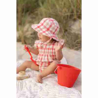 Jeune enfant jouant sur la plage avec un seau pliable corail Scrunch