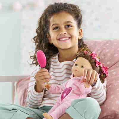 Enfant coiffant une poupée avec les accessoires Corolle