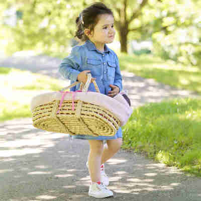 Fillette transportant le couffin peluche rose Corolle