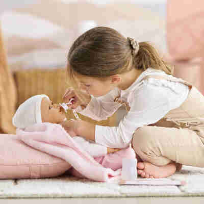 Enfant portant le poupon réaliste Rose Corolle