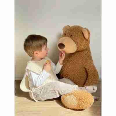 Enfant assis à côté de la grande peluche Anatole l'ours