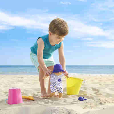 Enfant jouant avec Bébé Bain Marin Corolle dans le sable