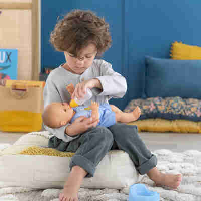 Enfant nourrissant le poupon Paul fait pipi avec son biberon