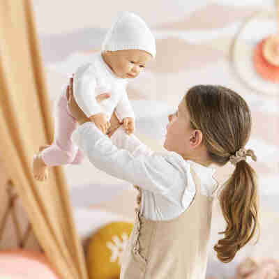 Enfant portant le poupon réaliste Rose Corolle