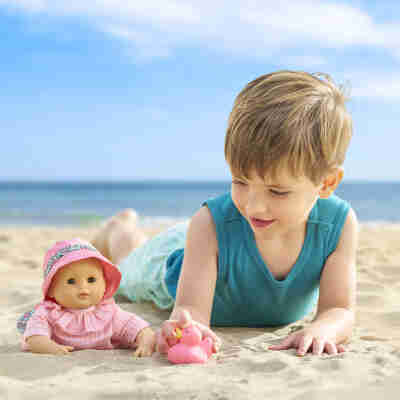 Enfant jouant avec Bébé Bain Coralie Corolle sur la plage