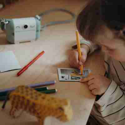 Enfant personnalisant une photo imprimée avec des feutres