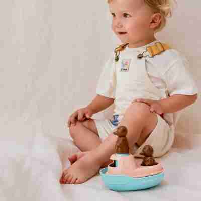 Ptit Loustic – Magasin de jeux et jouets à Saint-Étienne 14 Enfant assis près du petit bateau de bain Petit Ours Brun menthe