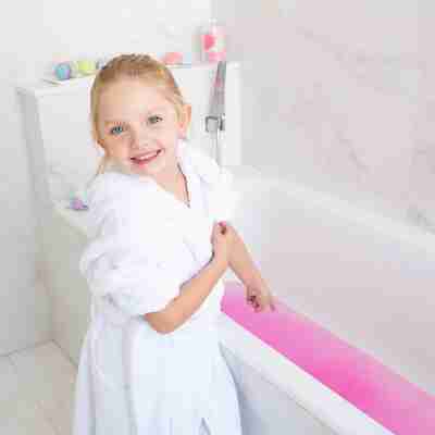 Enfant utilisant une bombe de bain colorée dans sa baignoire