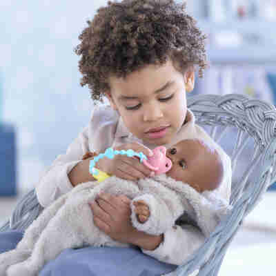 Enfant jouant avec un poupon Corolle et sa tétine sonore