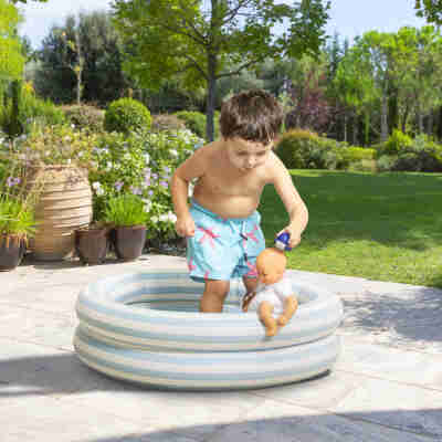 Enfant jouant avec le poupon Bébé Bain Marin Corolle dans une piscine