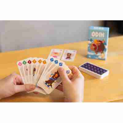 Main de joueur tenant des cartes du jeu Odin avec la boîte en arrière-plan