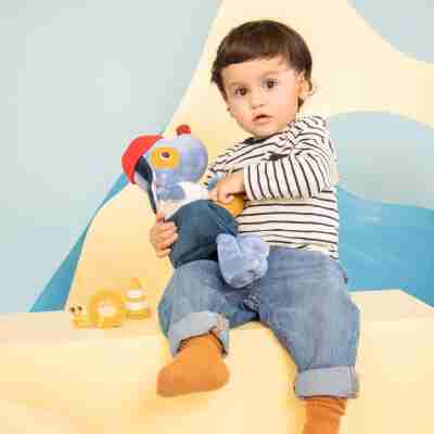 Un jeune enfant assis tenant la peluche d'activités Jules le chien bricoleur Lilliputiens