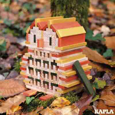 Maison construite avec des planchettes Kapla naturelles orange jaunes et vertes dans un décor d’automne