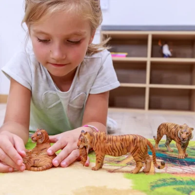 Enfant jouant avec plusieurs figurines de tigres Papo