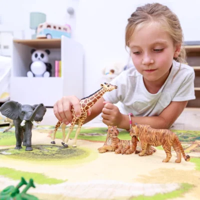 Enfant jouant avec la tigresse et son bébé Papo parmi des figurines d’animaux sauvages