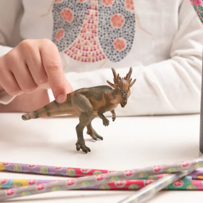 Enfant manipulant la figurine Stygimoloch Papo lors d’un jeu avec des dinosaures