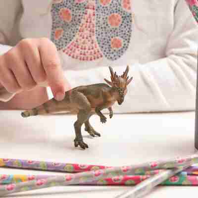 Enfant manipulant la figurine Stygimoloch Papo lors d’un jeu avec des dinosaures