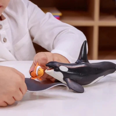 Enfant jouant avec la figurine Orque Papo et différentes figurines d’animaux marins