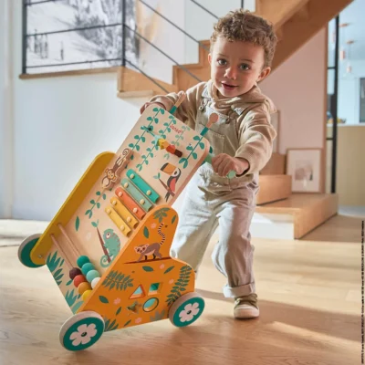 Enfant faisant ses premiers pas avec le chariot de marche Tropik Janod
