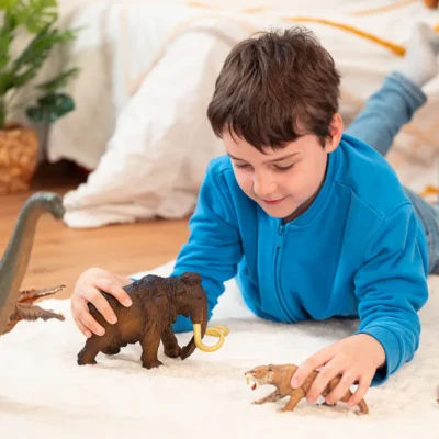Enfant jouant avec la figurine Mammouth Papo et plusieurs animaux préhistoriques
