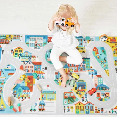Enfant jouant avec des petites voitures sur le tapis Ville Cross Roads Janod